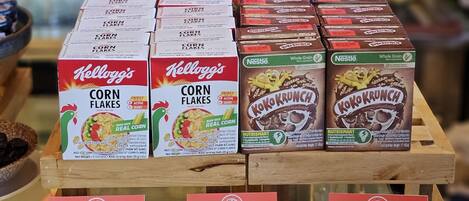 Eine Präsentation von Getreideboxen, darunter Kellogg's Corn Flakes, Nestle's Koko Krunch und andere Trockengebäcke.
