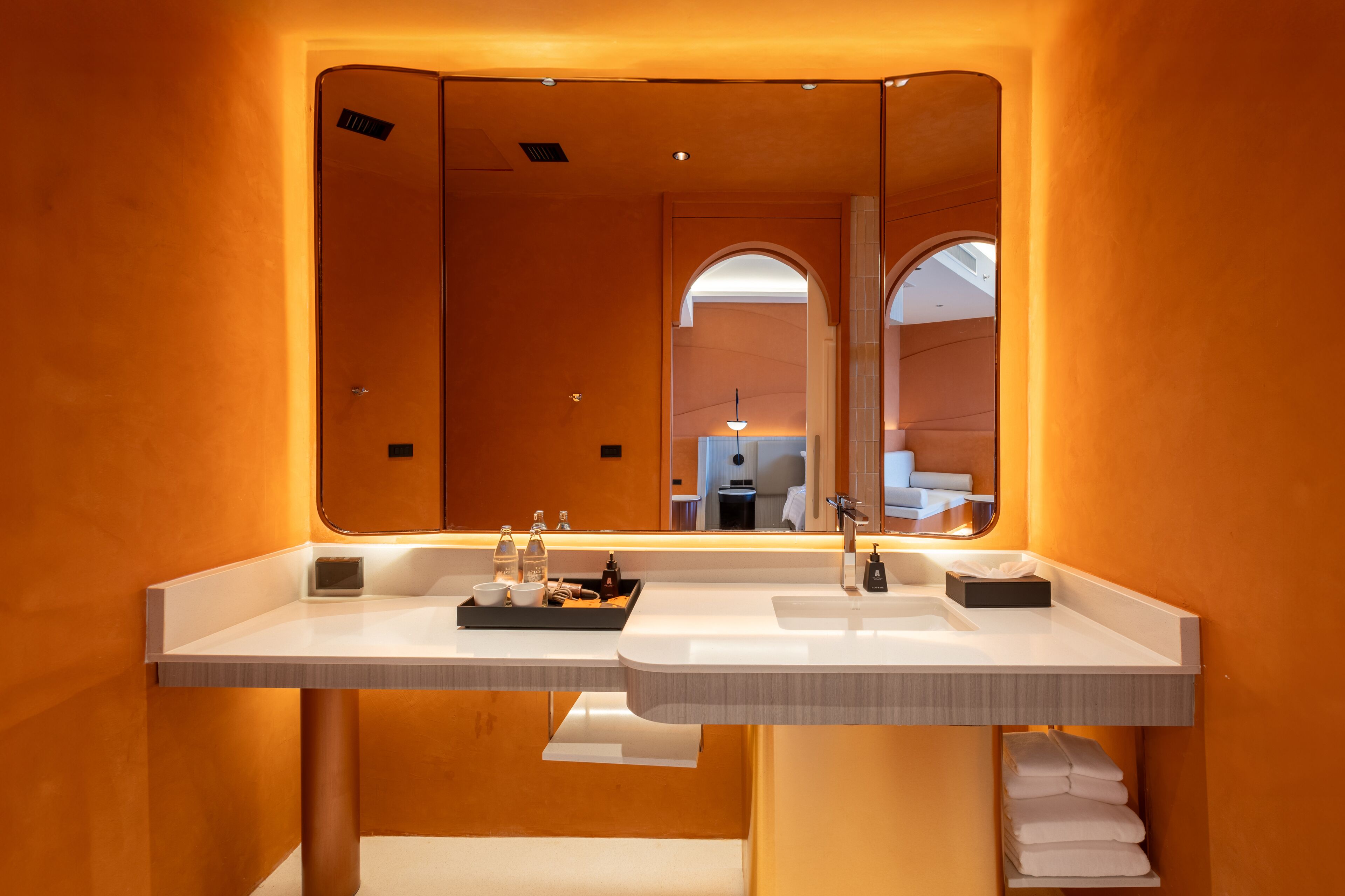 Une salle de bain moderne avec deux lavabos, un grand miroir et un porte-serviettes.