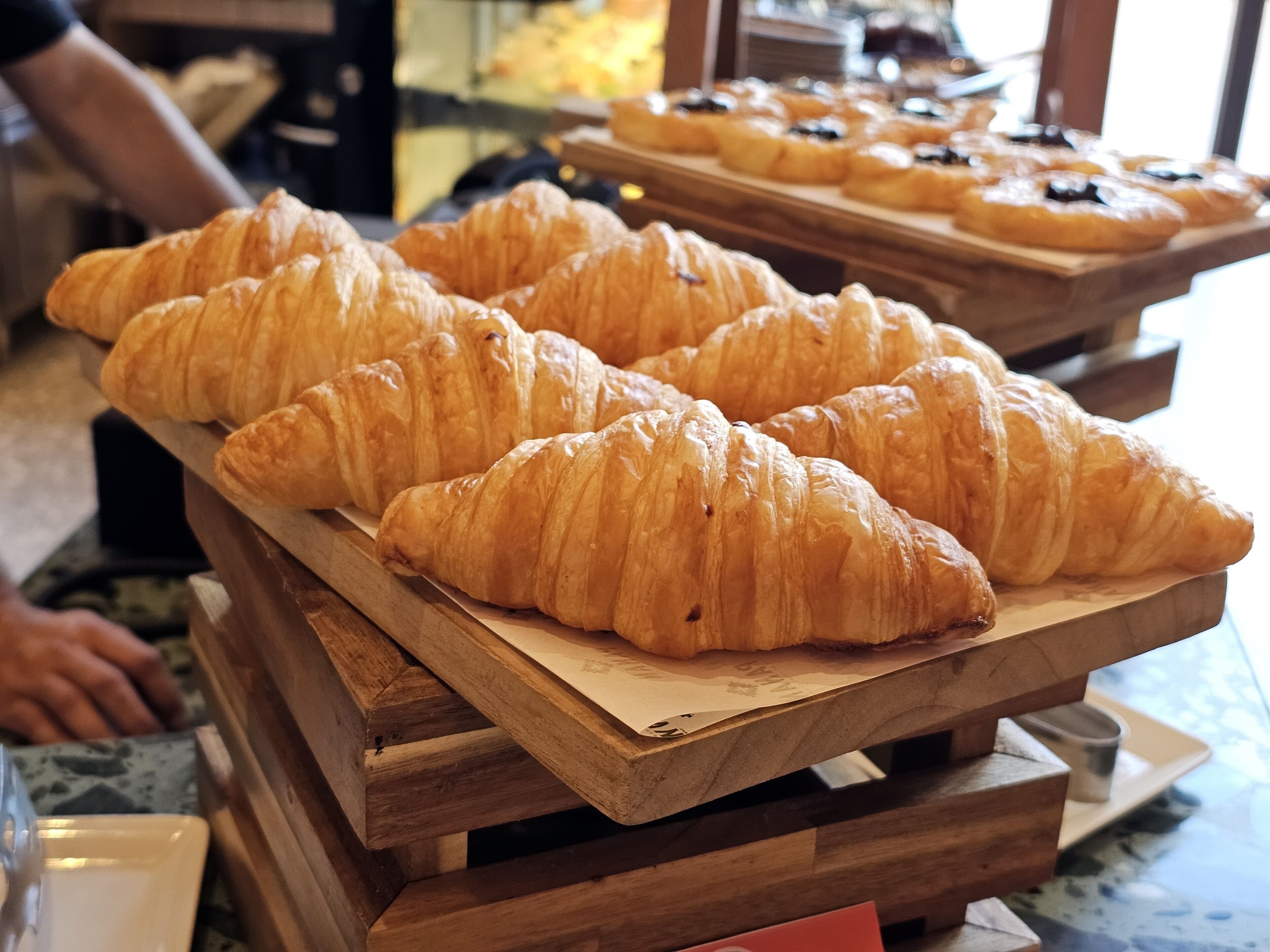 A display of croissants on wooden stands in a bakery.