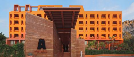 A modern hotel with a distinctive orange facade, multiple balconies, and a prominent entrance with a wooden overhang.