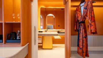 Een hotelbadkamer met een grote spiegel, een wastafel en een badjas hangend aan een rek.