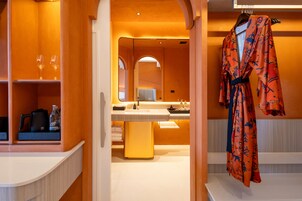 Een hotelbadkamer met een grote spiegel, een wastafel en een badjas hangend aan een rek.