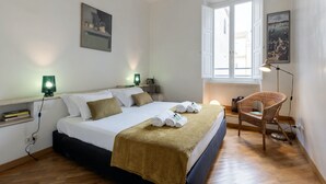 Une chambre à coucher avec un lit, une chaise, une fenêtre et des œuvres d’art accrochées aux murs.