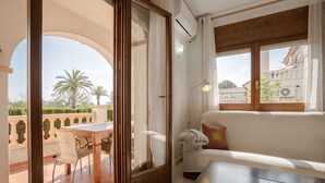A room with a balcony, a sofa, a table, and a chair.