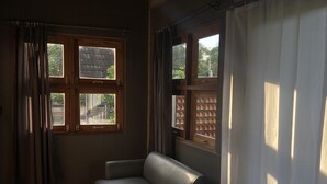 Una habitación con sofá, ventana con cortinas y luces colgantes en el techo.