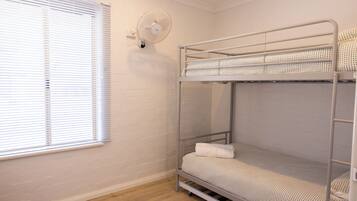 Dormitorio con literas, ventana y ventilador de pared.