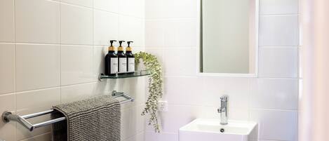 A bathroom with white tiles, a towel rack, a sink, and a mirror.