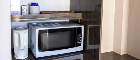 Una kitchenette compacta equipada con microondas, cafetera y refrigerador.