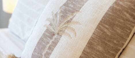 A close-up of a sofa with striped cushions and a palm leaf design.
