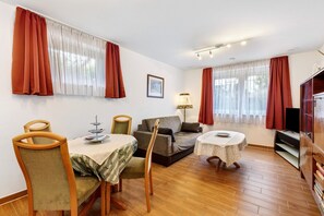 Una sala de estar con una mesa de comedor, sillas, un sofá y un televisor.
