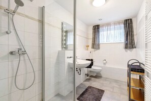 Une salle de bain moderne avec une douche à parois de verre, un lavabo, des toilettes et une fenêtre avec des rideaux.
