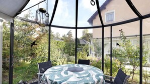 Ein Wintergarten mit rundem Tisch, Stühlen und einem Vogelkäfig.