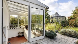 Ein Wintergarten mit Schiebeglastür, einem kleinen Tisch und einer Topfpflanze darin.