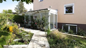 Ein Wintergarten mit Glasdach, einem Kiesweg und einem Garten mit verschiedenen Pflanzen und Blumen.