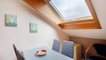A room with a skylight, a table with a bowl, and two chairs.