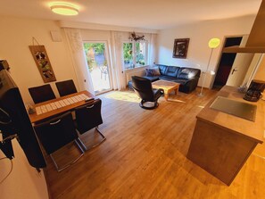 A modern living room with a dining area, a sofa, a coffee table, and a kitchen area.