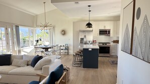 A modern kitchen with white cabinets, a central island, and stainless steel appliances.