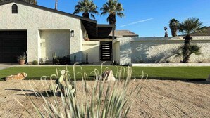 A modern house with a garage, a patio, and a well-maintained lawn.