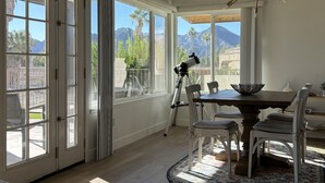 A dining area with a telescope, large windows, and a view of mountains.