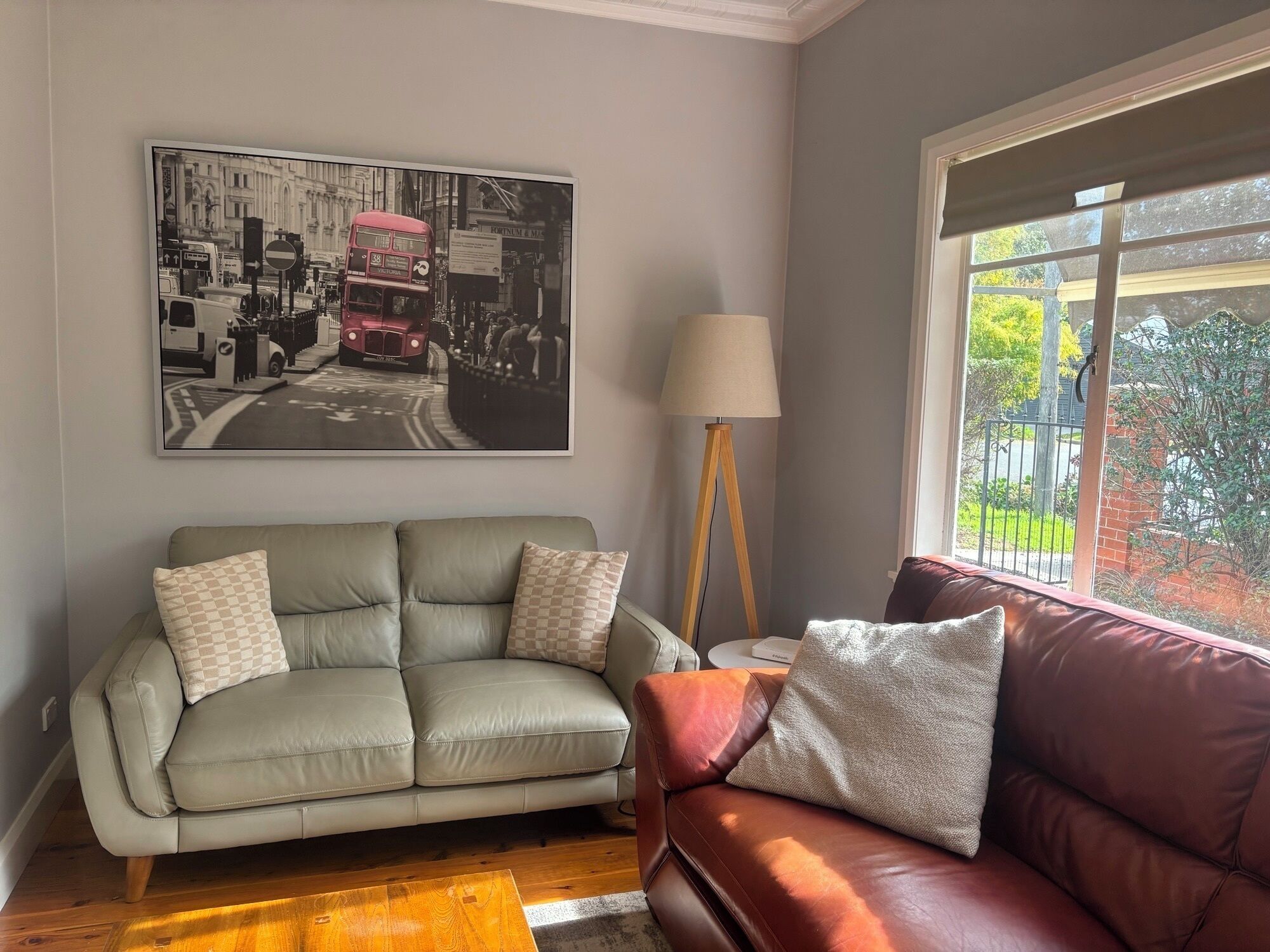 Ein Wohnzimmer mit einem grauen Sofa, einem roten Sofa, einer Lampe und einem großen Schwarzweißfoto an der Wand.