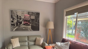A living room with a grey sofa, a red sofa, a lamp, and a large black-and-white photograph on the wall.