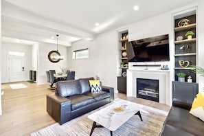 Relax in this stylish living room with a sofa, coffee table, flat-screen TV, and dining area.