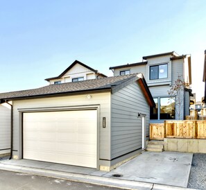 Situated in a suburban neighborhood, this home features a garage door, a small porch, and a brick exterior with a sloped roof and multiple windows.