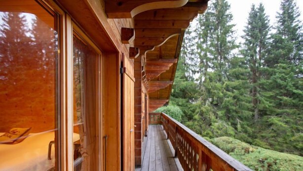 A wooden deck with a railing overlooking a forested area. - Chalet Le Haut Pré by Interhome (Villars)