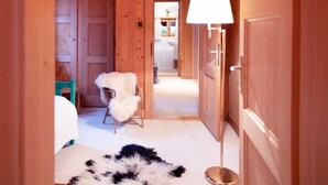 A wooden hallway with a white fur chair, a black and white fur rug, and a floor lamp. - Chalet Le Haut Pré by Interhome (Villars)