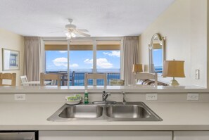 A hotel room with a balcony, a double sink, a ceiling fan, and a view of the ocean.