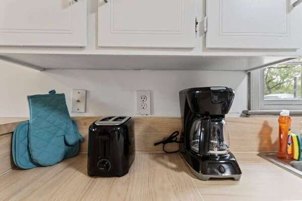 A kitchen with a toaster, coffee maker, and a teal oven mitt on the counter. - Midtown, Fenced Yard & Patio- White Acres Retreat (Montgomery)
