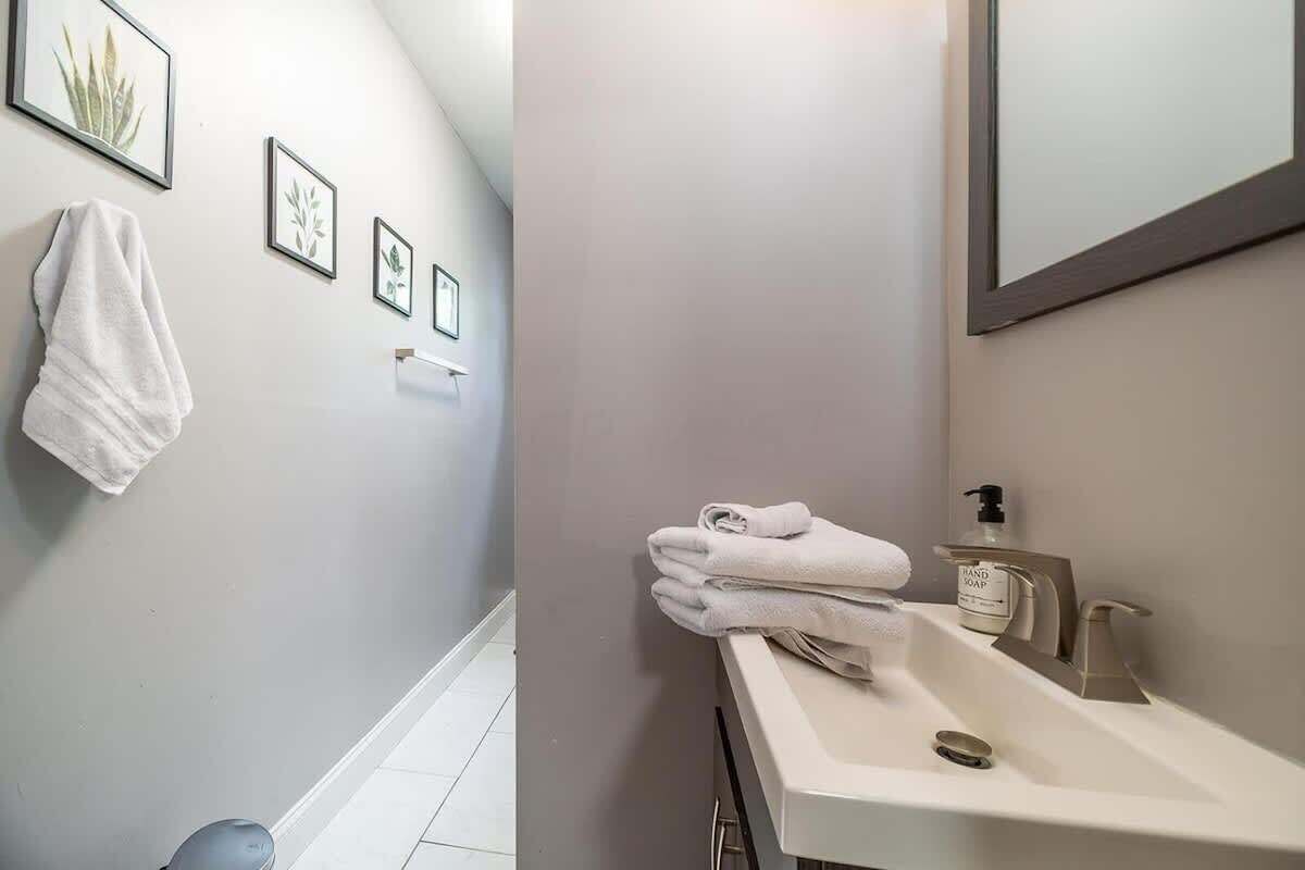 Une salle de bain avec un lavabo blanc, un porte-serviettes sur lequel est posée une serviette, et des reproductions encadrées de motifs botaniques accrochées au mur.