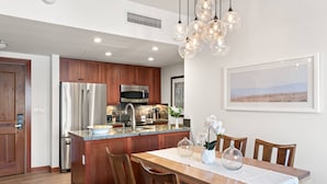 Una cocina moderna con armarios de madera, electrodomésticos de acero inoxidable y un comedor con mesa y sillas de madera.