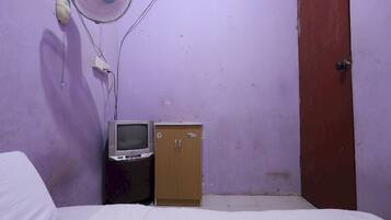 A small room with a bed, a television, a cabinet, and a door.