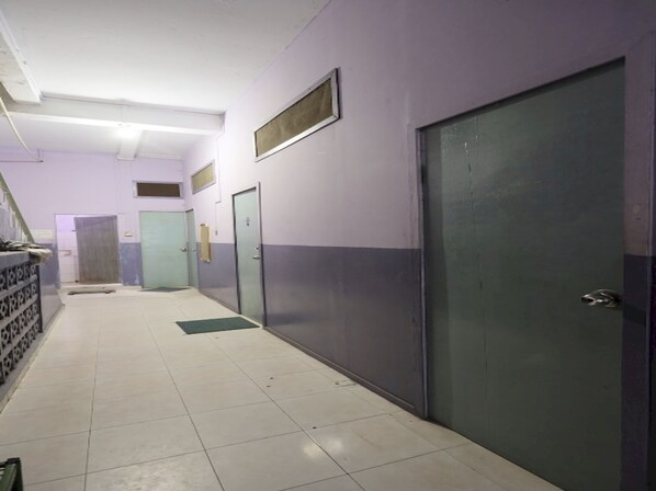 A hallway with doors on both sides, tiled floor, and a staircase at the end.