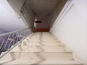 A staircase with a metal handrail, leading to a landing with a door. - SPOT ON 93276 Fendi 2 Homestay SyariahNearPelabuhan Feri Batam Centre (Batam)