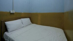 A single bed with white bedding in a room with blue and yellow walls. - SPOT ON 93276 Fendi 2 Homestay SyariahNearPelabuhan Feri Batam Centre (Batam)