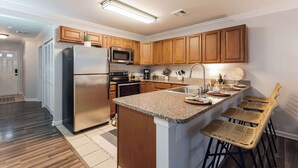 A modern kitchen with wooden cabinets, stainless steel appliances, and a granite countertop.