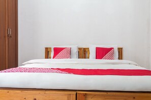 A bed with white and red bedding, a wooden headboard, and a wooden wardrobe to the left. - Capital O 93279 Asyoka Penginapan Pasutri (Bekasi)