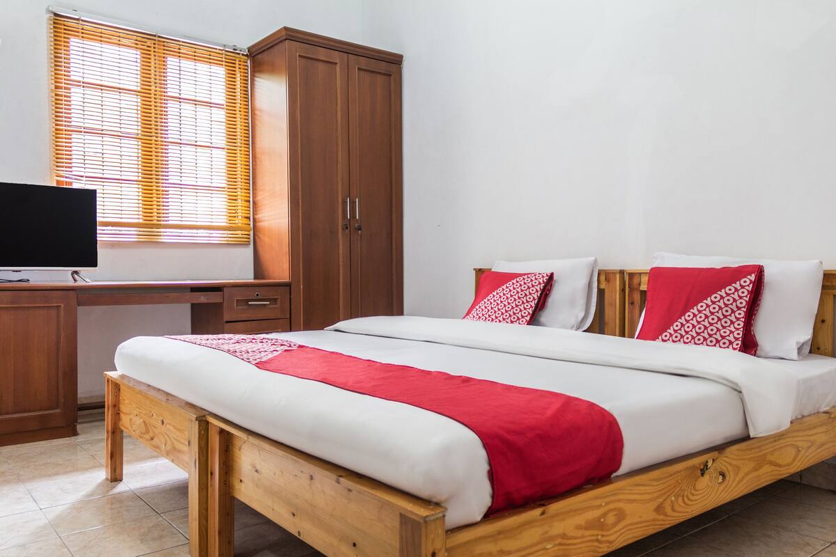 Ein Schlafzimmer mit einem hölzernen Bett, einem Schreibtisch mit Fernseher und einem Kleiderschrank.