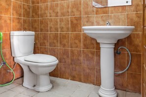 A bathroom with a toilet and a pedestal sink. - Capital O 93279 Asyoka Penginapan Pasutri (Bekasi)