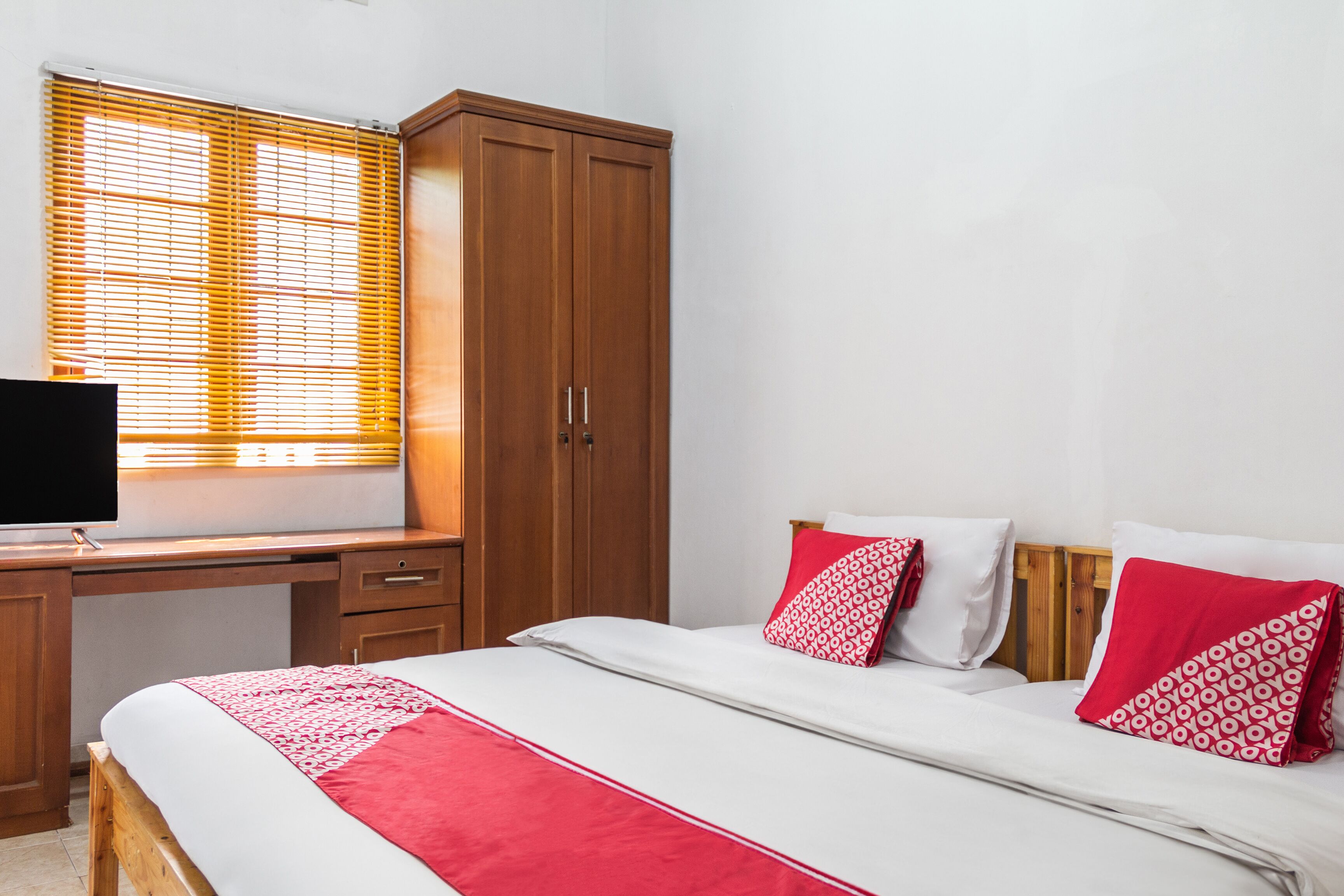 A bedroom with a bed, a desk, a television, and a wardrobe.