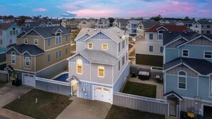 Un quartiere residenziale con diverse case a due piani, ciascuna dotata di garage e giardino anteriore.