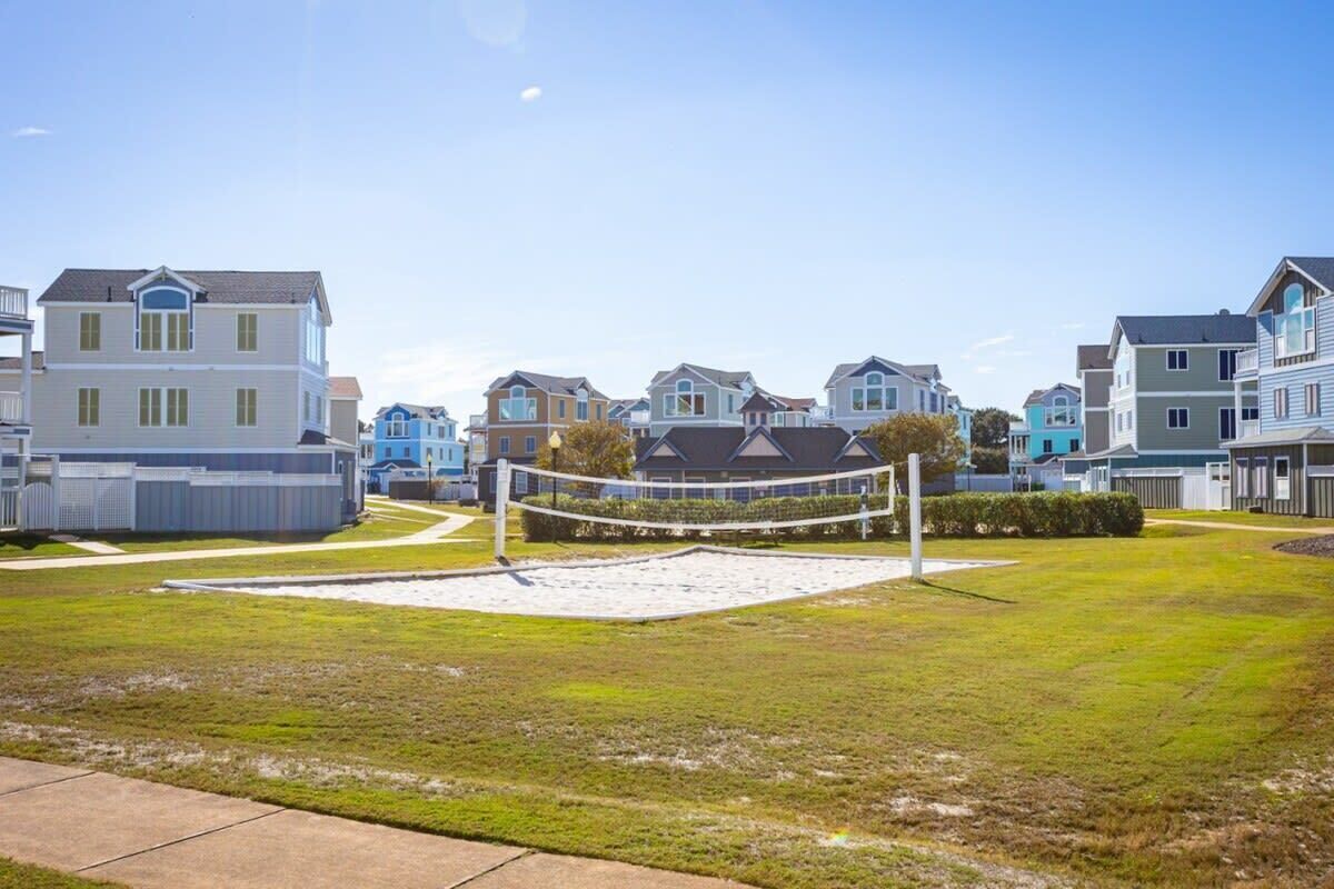 A residential area with houses, a volleyball net, and a grassy field.