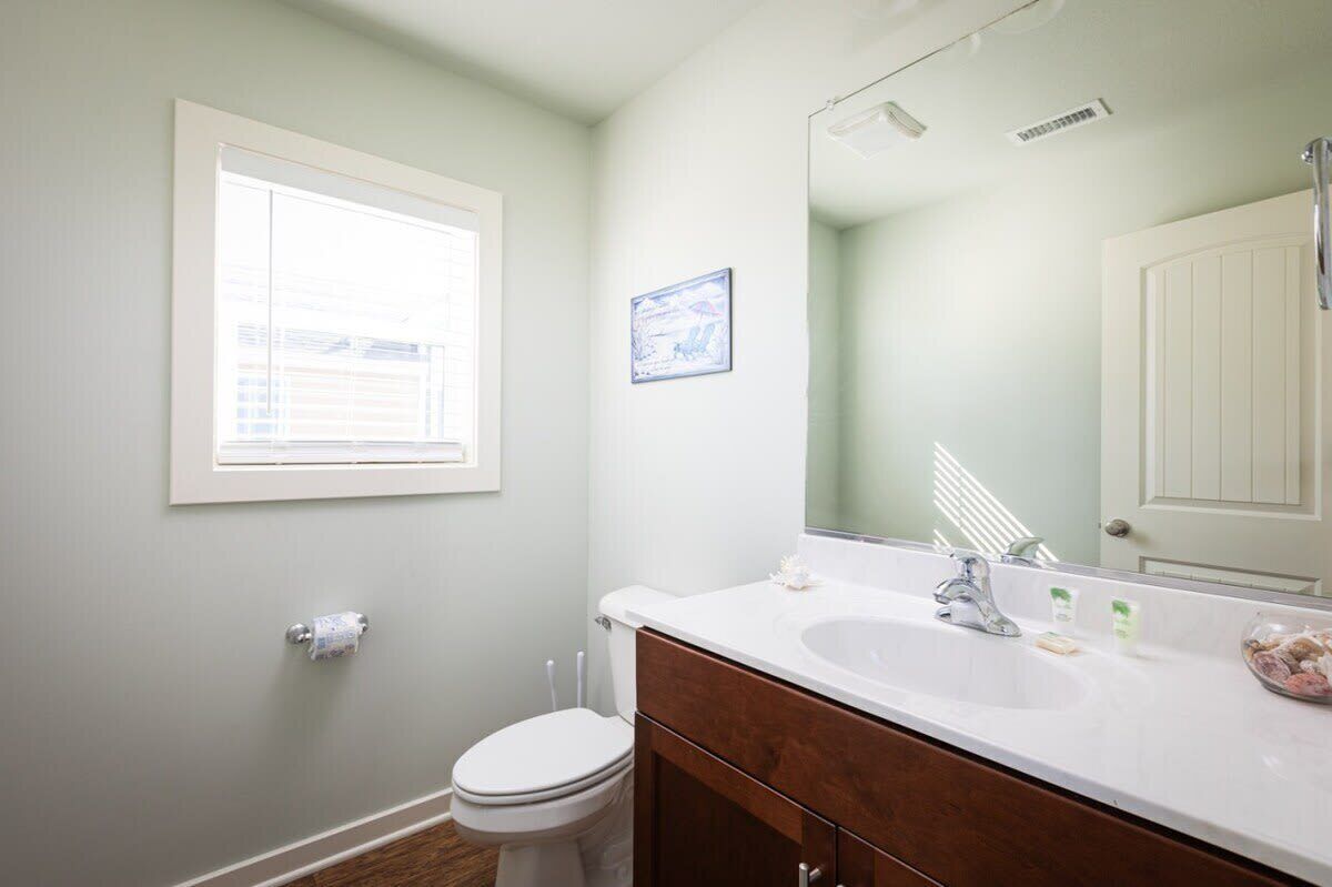 A bathroom with a white toilet, a white sink, and a large mirror.
