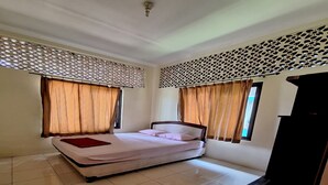 Une chambre à coucher avec un lit, des rideaux, un panneau décoratif au mur et un sol carrelé.