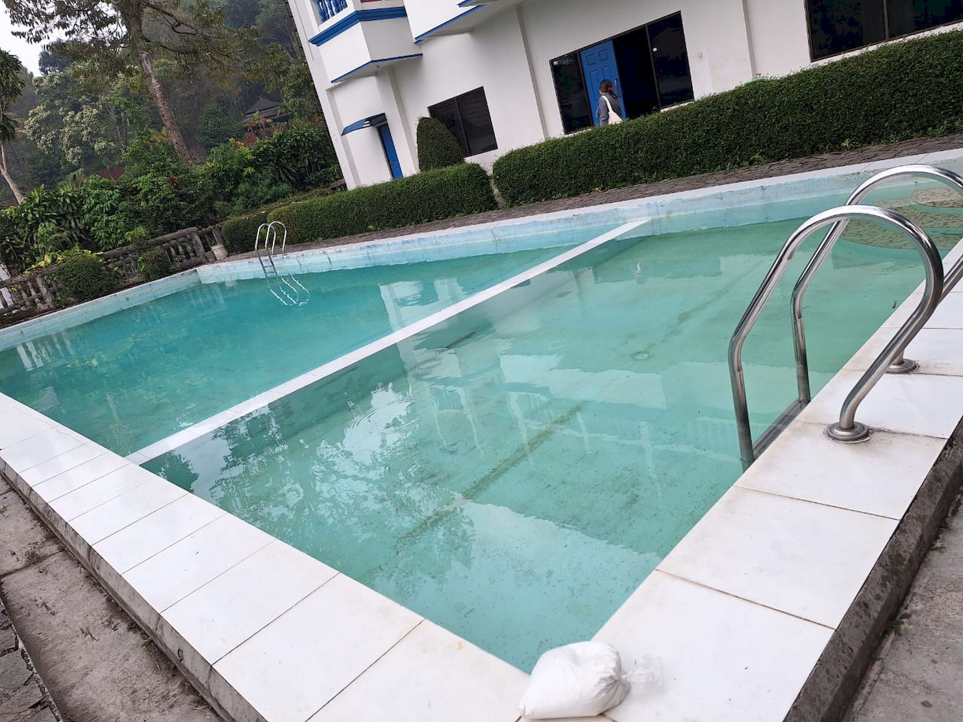 Una piscina con agua cristalina, rodeada por un deck de baldosas blancas.