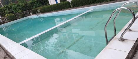 Una piscina con agua cristalina, rodeada por un deck de baldosas blancas.