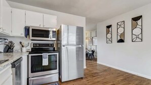 Een moderne keuken met roestvrijstalen apparatuur, witte kasten en een houten vloer.