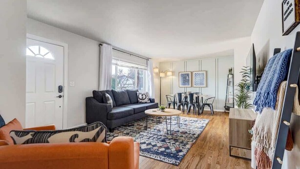 Een woonkamer met een bank, een salontafel en een eethoek met stoelen.